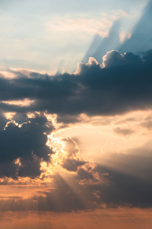Free Dramatic clouds with sun rays during a vibrant sunset. Stock Photo