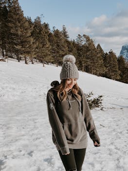 Smiling woman in winter attire hiking through snowy Canadian landscape, enjoying nature.