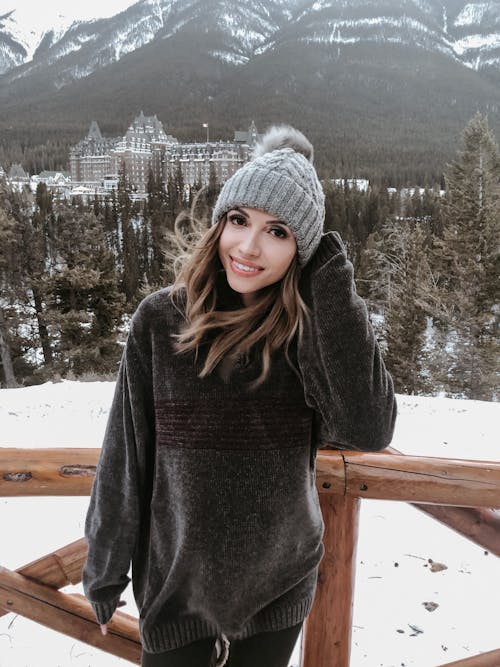 Woman in Gray Knit Cap and Gray Sweater Standing on Snow Covered Ground