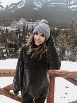 Young woman enjoying a snowy day in Banff National Park with a scenic mountain backdrop.