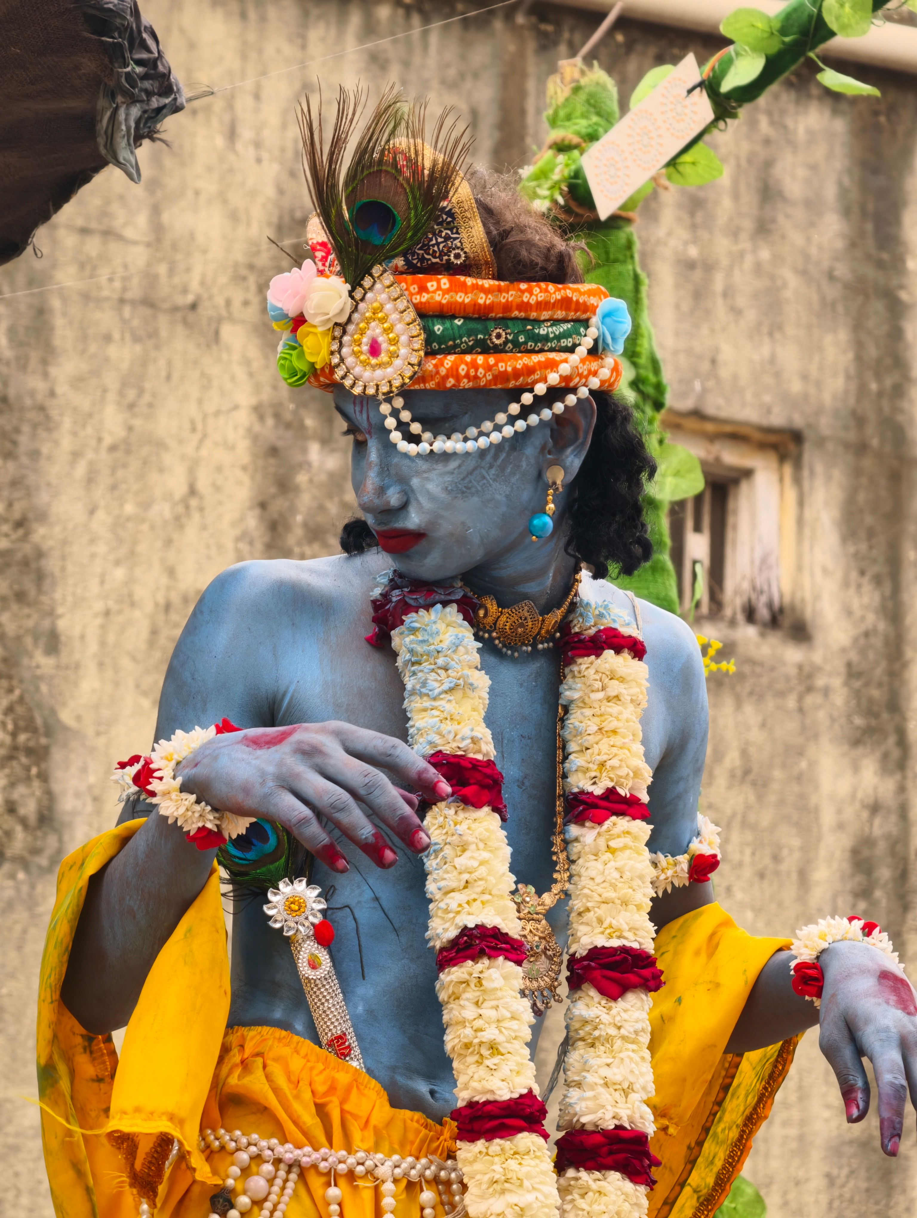 A person in vibrant traditional Indian attire and makeup participates in a cultural festival.