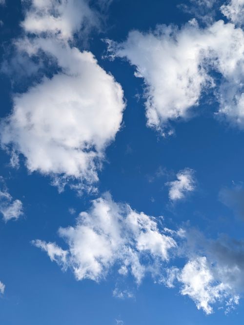 Free A clear blue sky featuring fluffy white clouds on a sunny day. Stock Photo