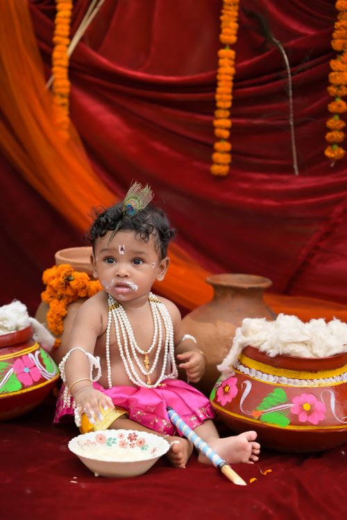 Free Cute baby dressed as Krishna with traditional Indian decorations in a festive setting. Stock Photo