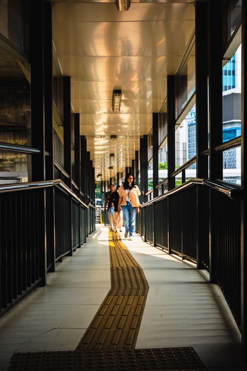 Free People walking through a pedestrian bridge in Jakarta, bright daylight casting shadows. Stock Photo