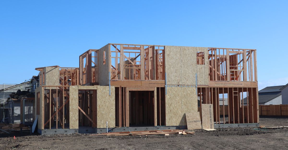 A wooden frame structure under construction for a new suburban house.