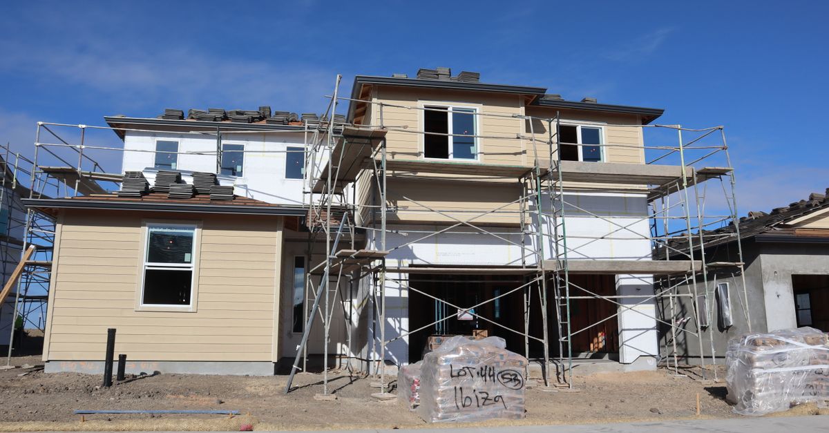 Under-construction house with scaffolding indicating active building progress under clear skies.