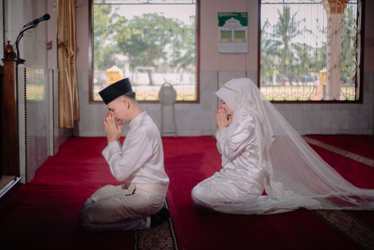 A bride and groom in traditional attire pray during their wedding in an Indonesian mosque. - Fotografer Sidoarjo