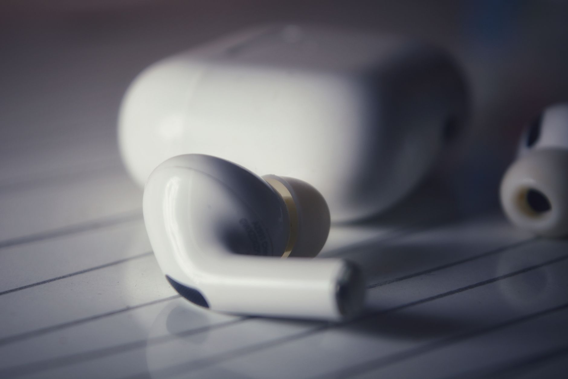 High-quality close-up image of white wireless earbuds with charging case on a lined surface.