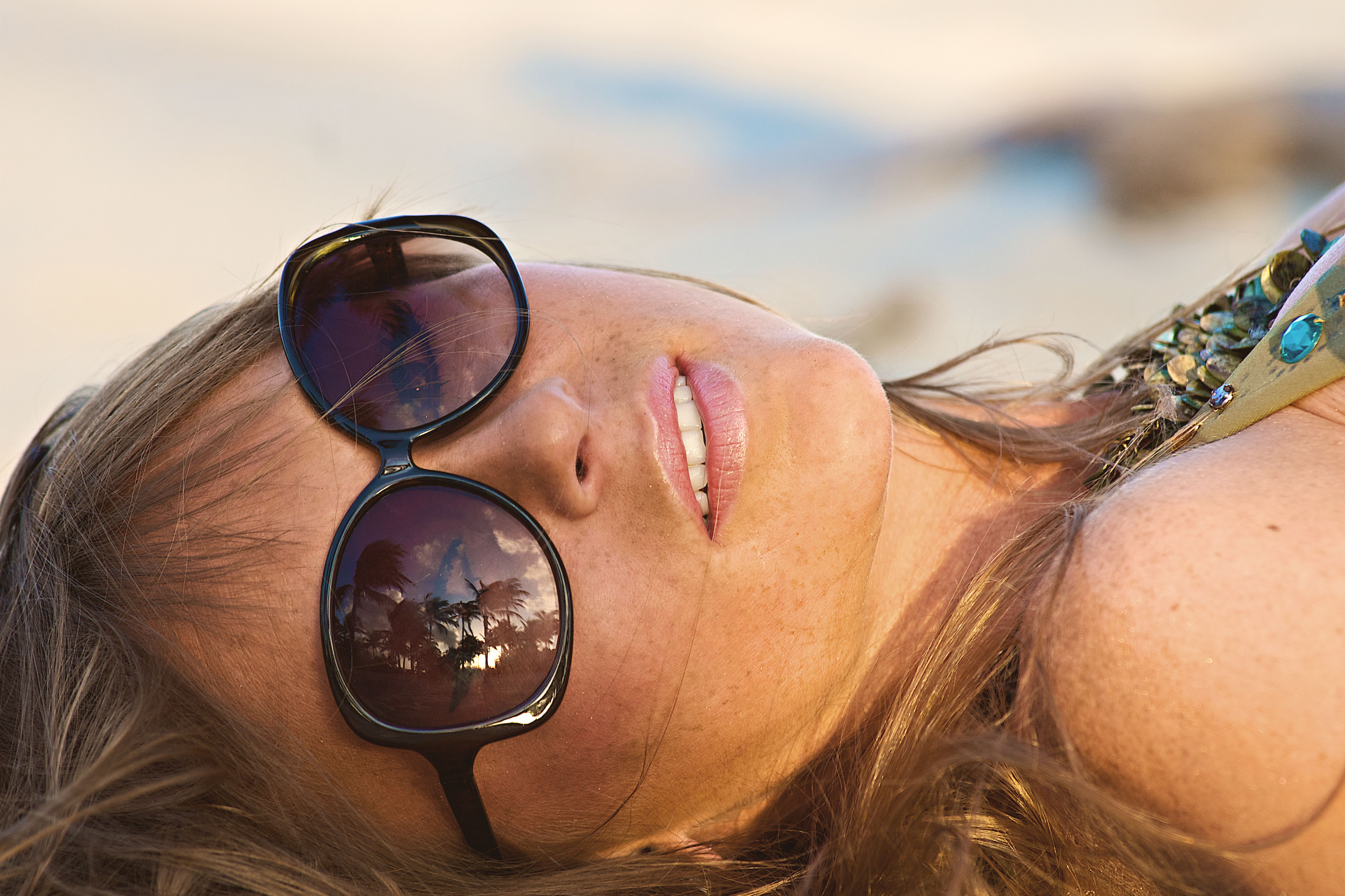 Close-up of a woman with sunglasses reflecting palm trees at Miami Beach.