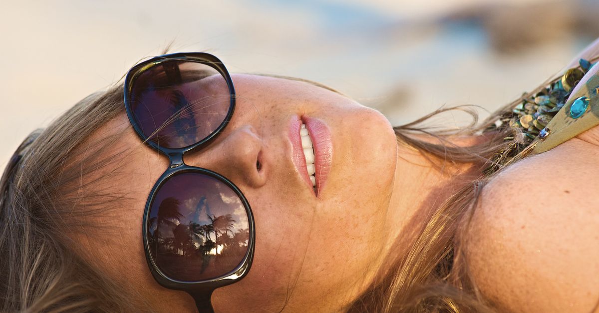 Close-up of a woman with sunglasses reflecting palm trees at Miami Beach.