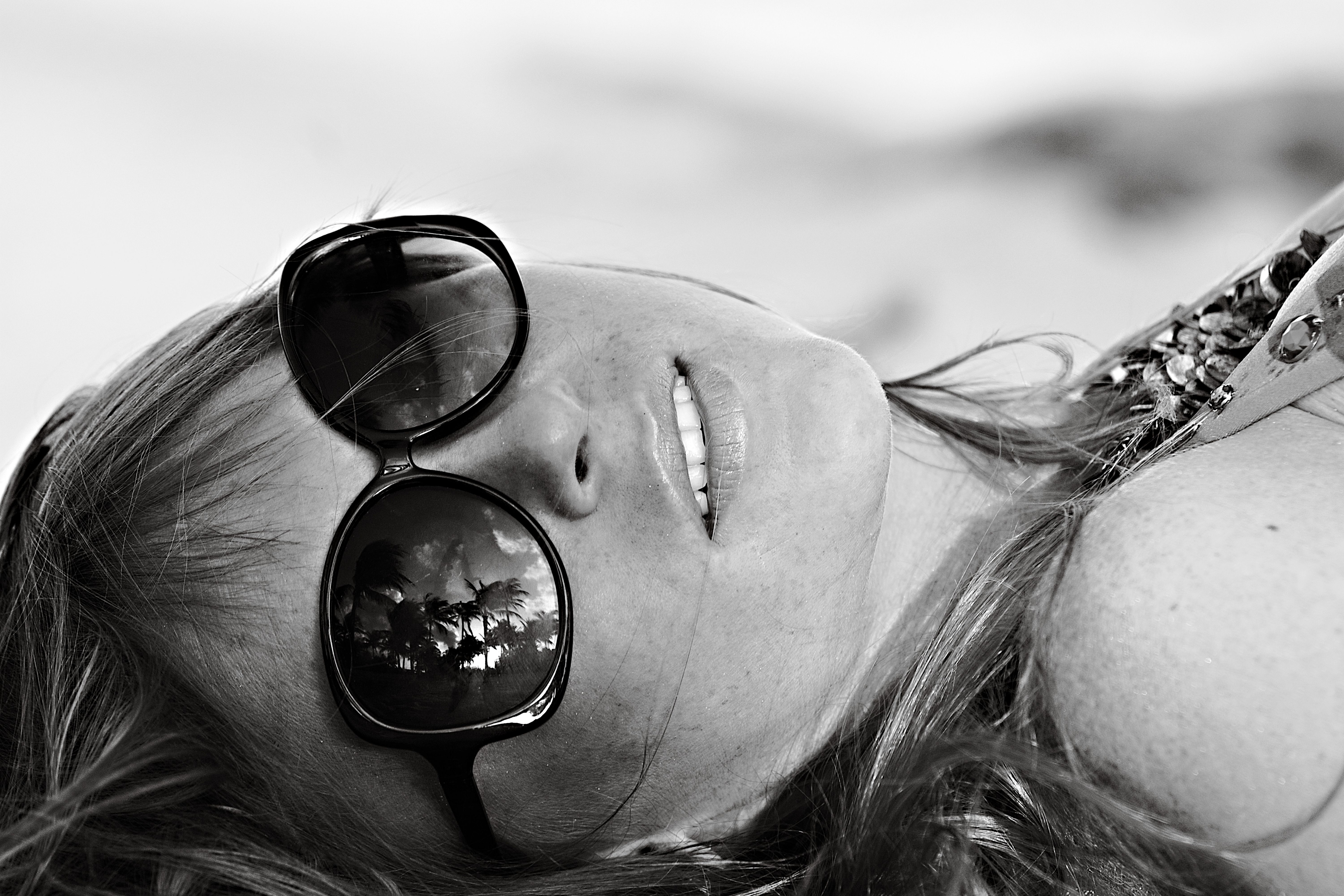 Woman enjoying the sun at Miami Beach. Palm reflections in sunglasses.