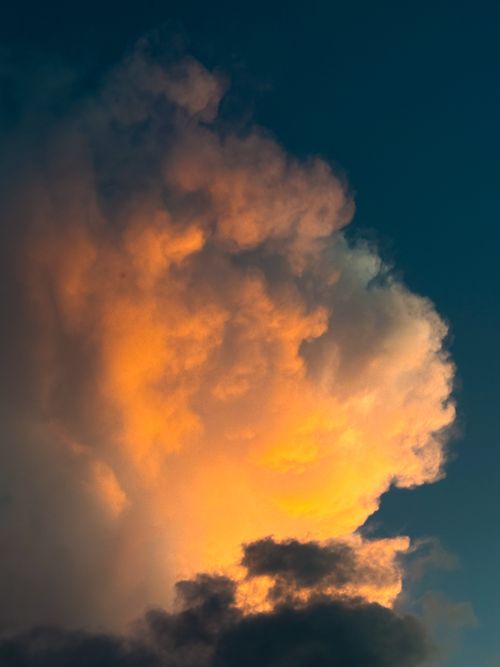 Free Vivid orange clouds illuminated by sunset create a dramatic effect against a dark sky. Stock Photo