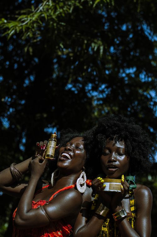 Free Two women enjoying beauty products under the sun, showcasing natural hair and radiant joy. Stock Photo