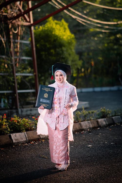 Free A proud graduate in traditional dress celebrates her achievement outdoors. Stock Photo