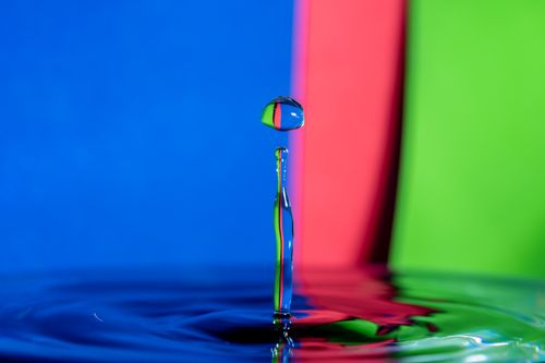 Free A dynamic water splash captured against a vibrant background, showcasing colors and reflections. Stock Photo