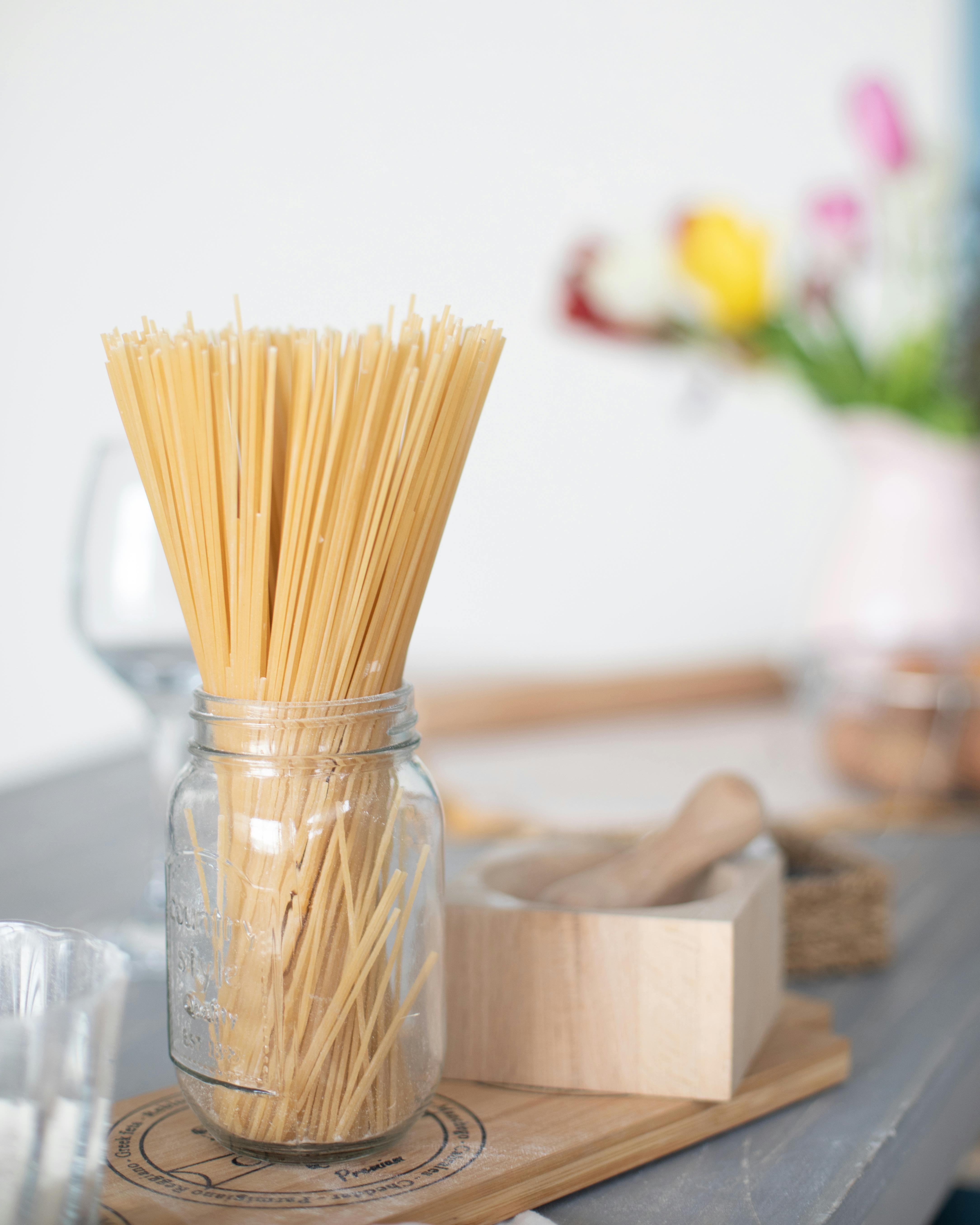 Aesthetic display of uncooked spaghetti in a glass jar, perfect for Italian cuisine themed photography.