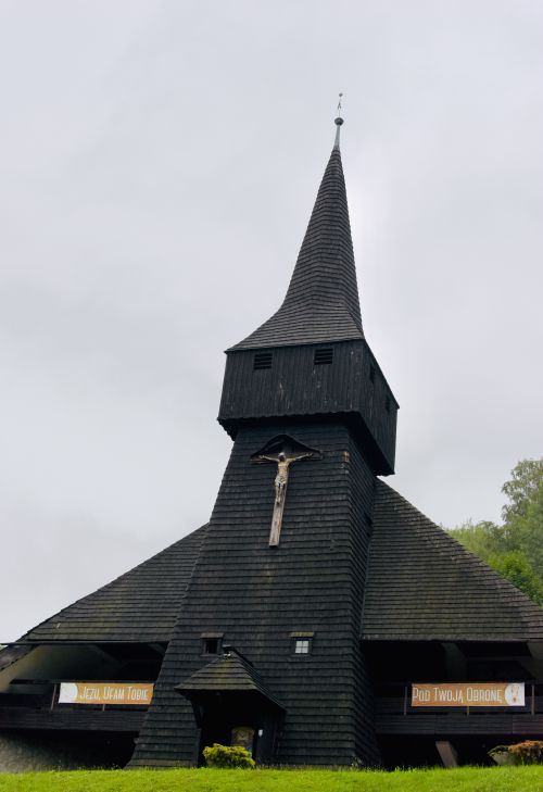 Free A traditional wooden church with a crucifix, set in the scenic hills of Wisła, Poland. Stock Photo