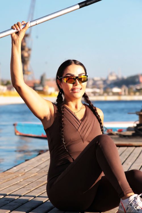 Free Woman in athletic wear doing exercises by the waterfront. Sunny day by the city skyline. Stock Photo