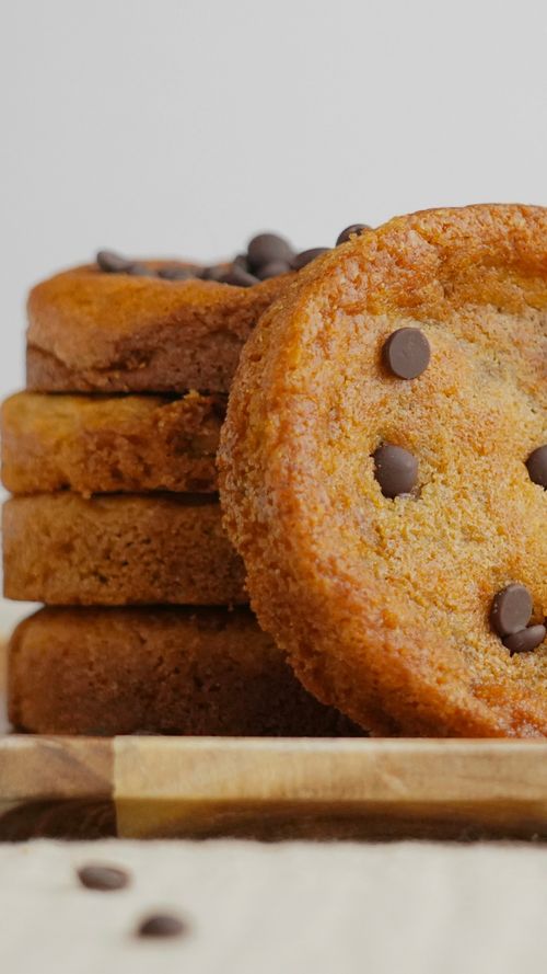 Free Close-up of freshly baked chocolate chip cookies stacked on a wooden board. Stock Photo