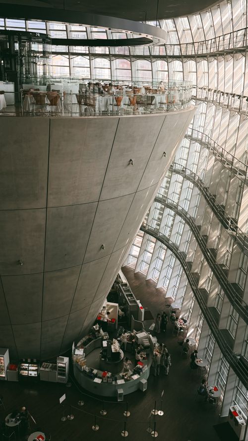 Free Interior of a modern building with curved concrete and glass architecture, featuring a cafe. Stock Photo