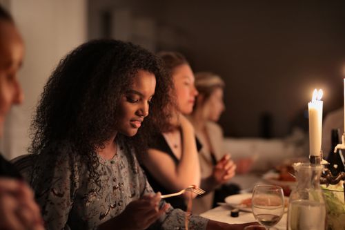 Free A diverse group enjoying a cozy, candlelit dinner together indoors. Stock Photo