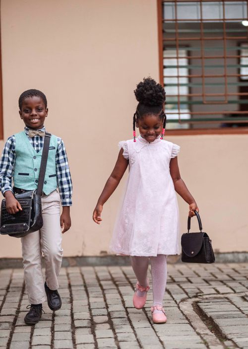 Free Two children in formal attire walking happily outdoors in Accra, Ghana. Stock Photo