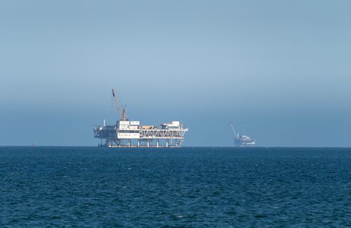 Free An offshore oil rig sits in calm ocean waters under a clear blue sky. Stock Photo