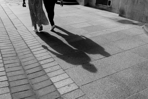 Free Two people walking on a street casting long shadows, in black and white. Stock Photo