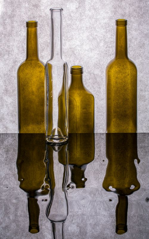 Free Creative arrangement of glass bottles displaying reflections on a smooth surface. Stock Photo