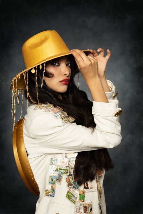 Free Fashion portrait of a woman in a golden hat and stamp-adorned jacket. Stock Photo