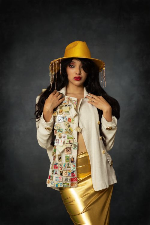 Free Fashionable woman with stamp-adorned jacket and yellow hat against dark background. Stock Photo