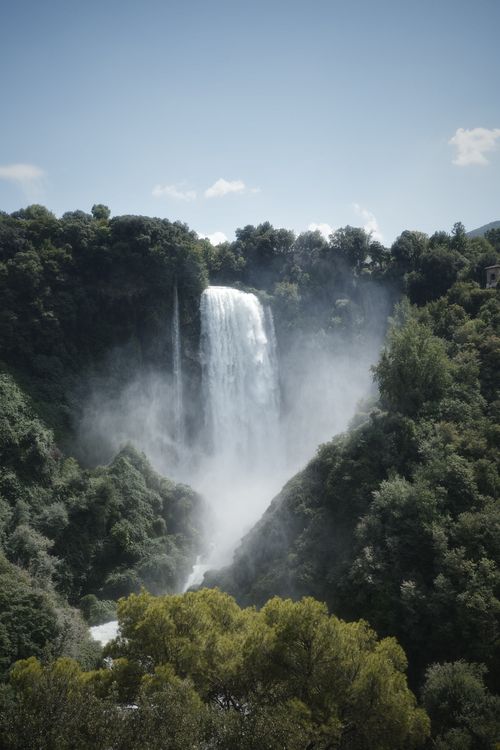 Free Majestic waterfall cascades in lush green Umbria, Italy during a sunny day. Stock Photo