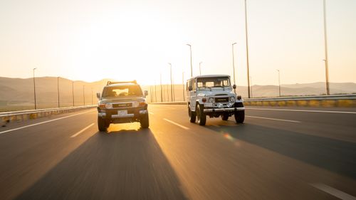 Free Two SUVs driving fast on a highway during sunrise, capturing dynamic motion. Stock Photo