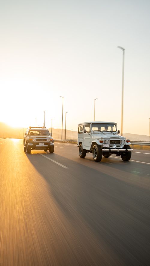 Free Two SUVs cruising on a highway at sunset, captured in motion. Stock Photo