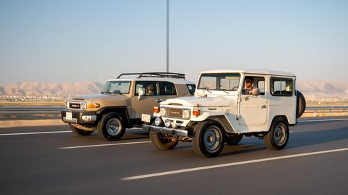 Free Two SUVs drive on a highway against a desert backdrop, illustrating contrast. Stock Photo