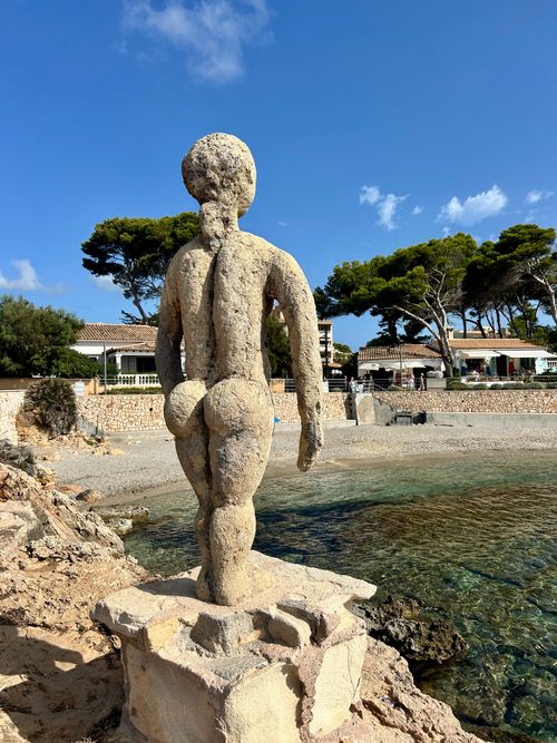 Free Stone sculpture overlooking the beach with clear blue sky and seaside view in Mallorca. Stock Photo
