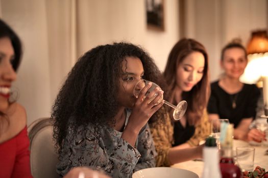 一群女性在室内享用舒适的晚餐，分享饮料与欢笑