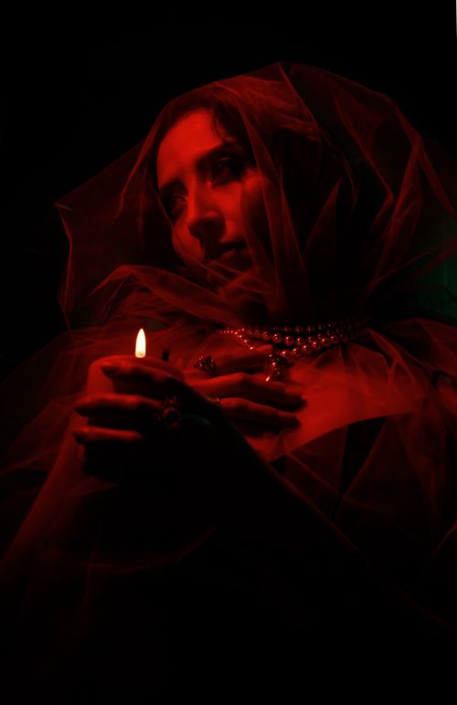 Free Mysterious woman with a red veil holding a candle, creating a dramatic and moody atmosphere. Stock Photo