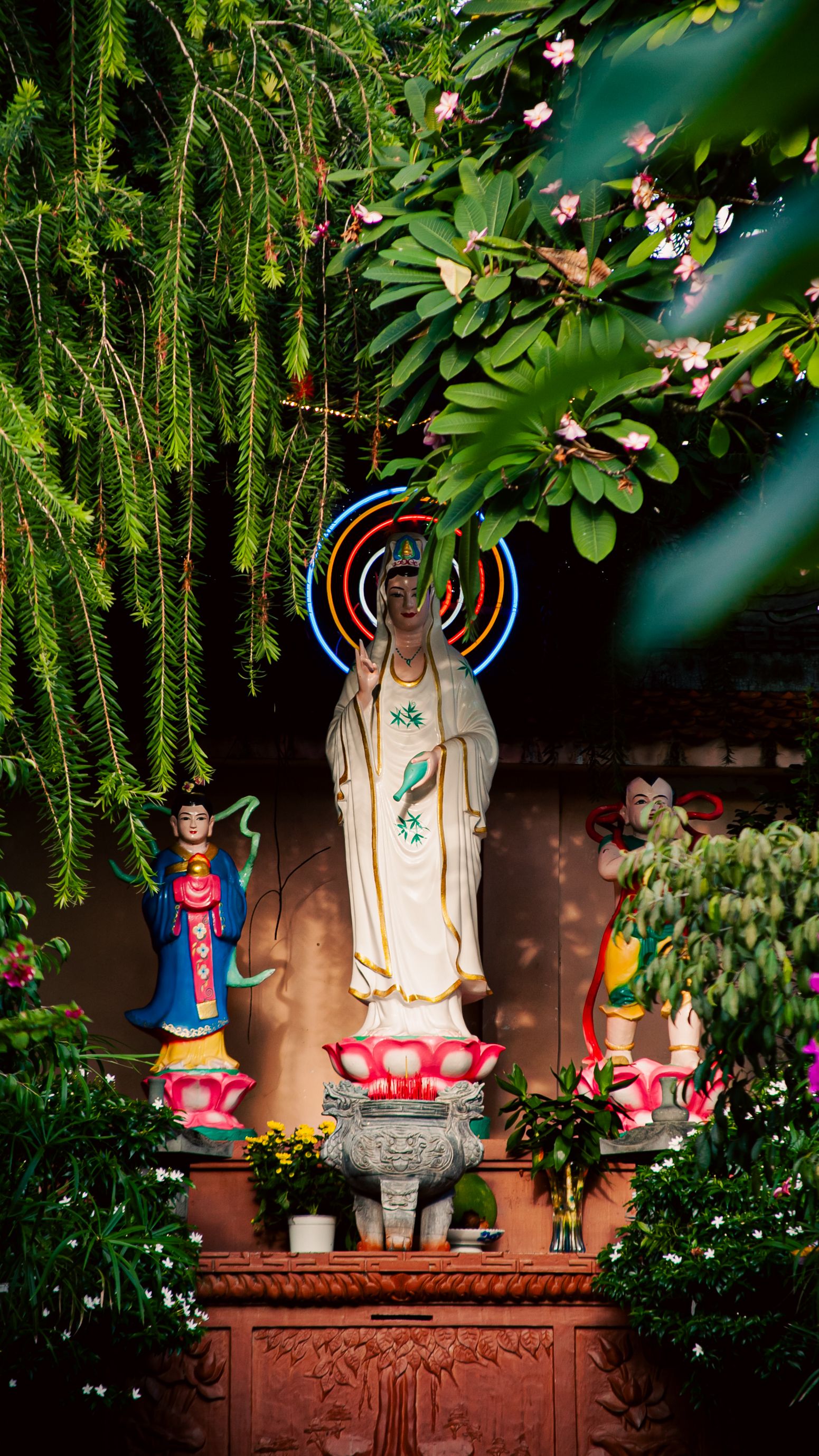 Serene Buddhist statues surrounded by vibrant foliage in Đồng Nai, Vietnam garden.
