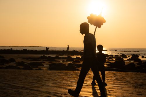 Free A mesmerizing silhouette of a person carrying balloons on a beach during sunset, capturing a serene moment. Stock Photo