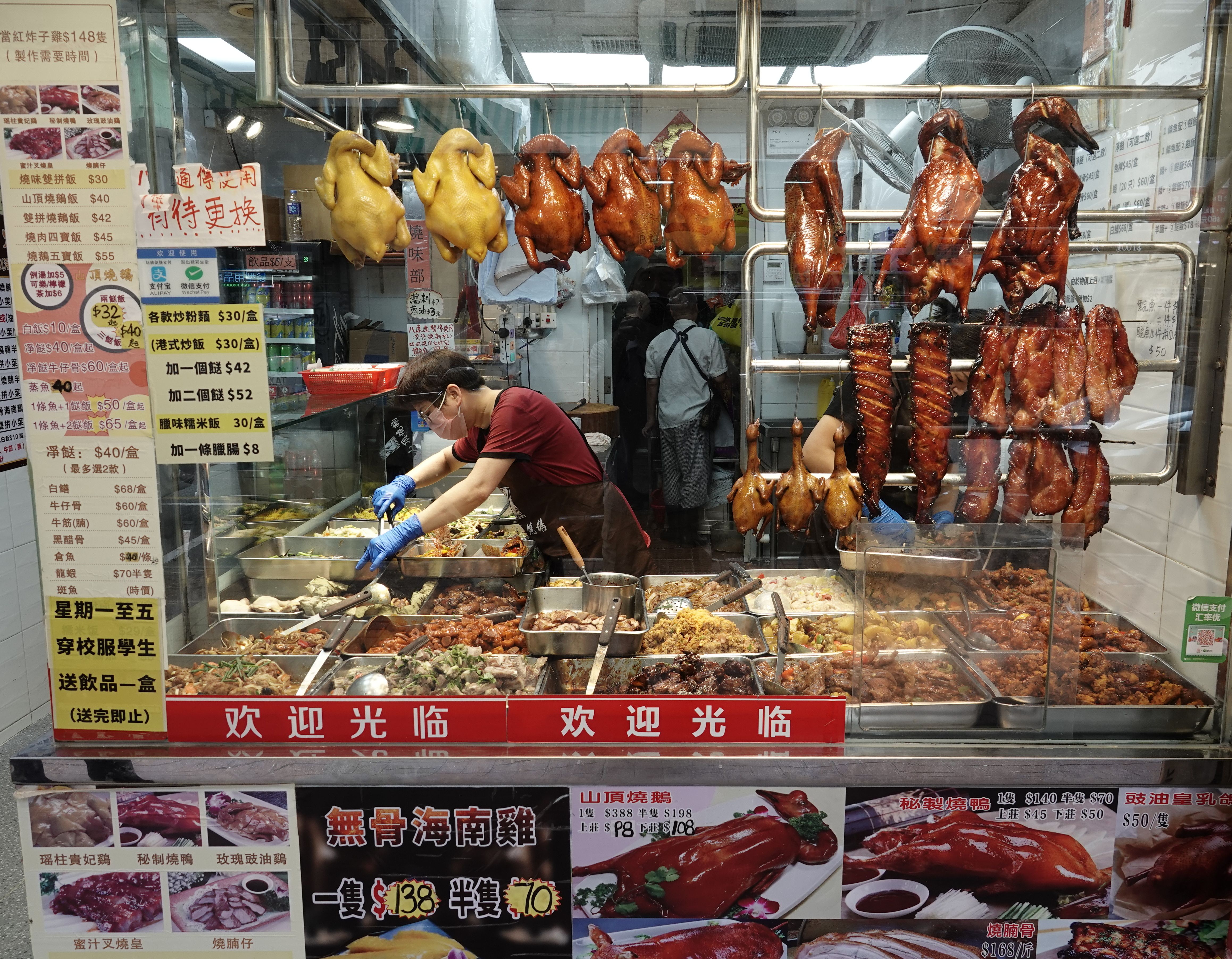 Discover traditional Cantonese roast meats at a bustling food stall in Kowloon, Hong Kong.