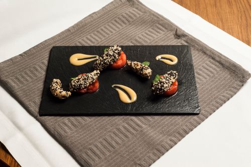 Free Elegant presentation of sesame-crusted chicken on slate with sauces and tomatoes. Stock Photo