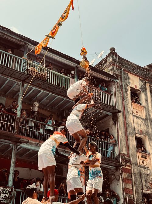 Free A vibrant capture of Dahi Handi festival with a human pyramid breaking a pot in an urban setting. Stock Photo