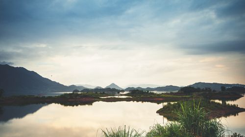 Free Peaceful landscape featuring a lake with mountainous backdrop under a cloudy sky. Stock Photo