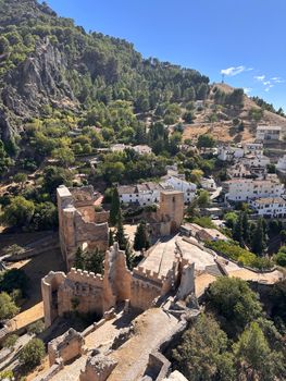 Stunning aerial view of La Iruela Castle amidst lush greenery and rustic townhouses in Andalucía.