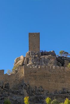 Stone castle tower with a clear blue sky, highlighting ancient architecture.