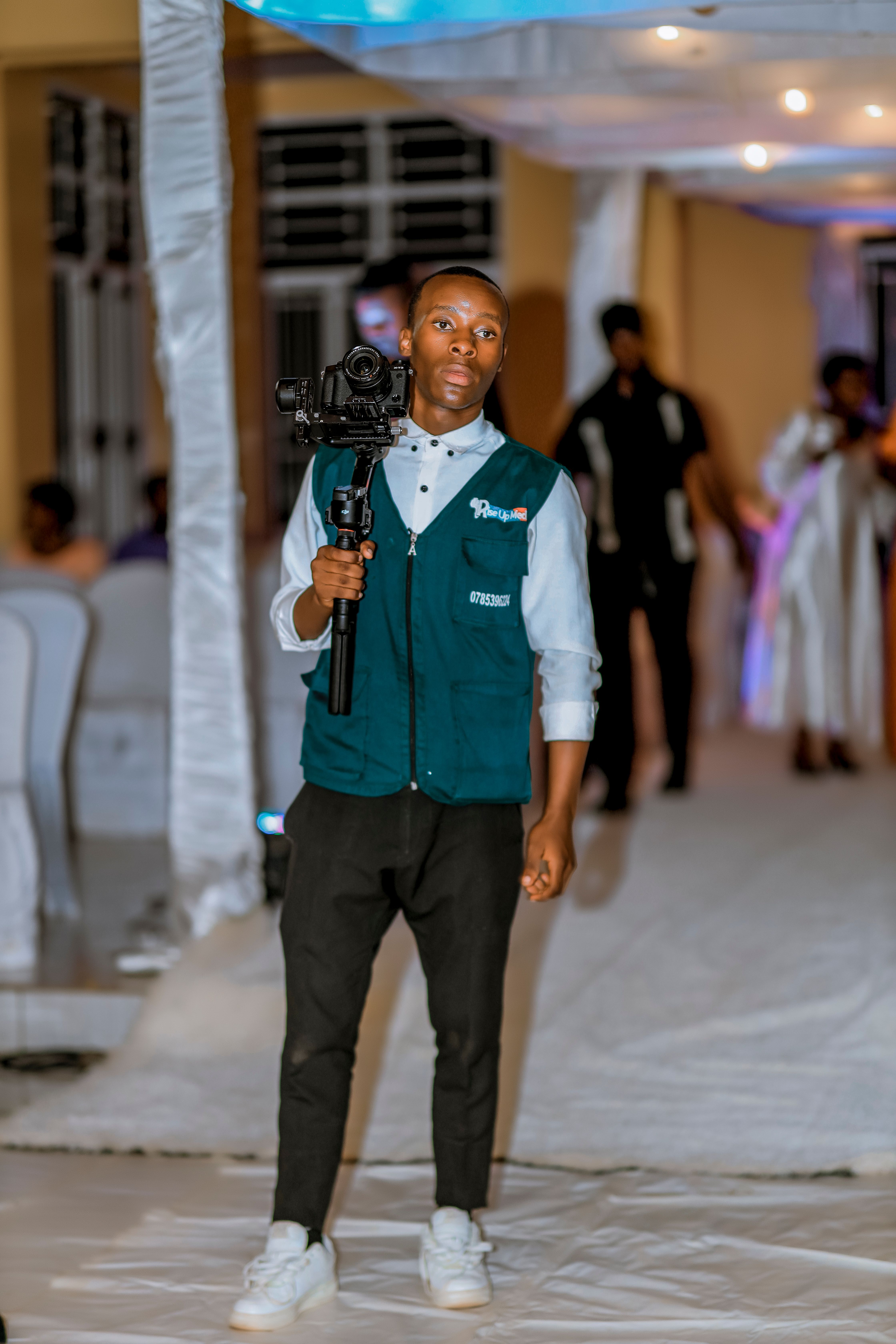 A professional videographer using a camera stabilizer at an indoor event in a formal setting.