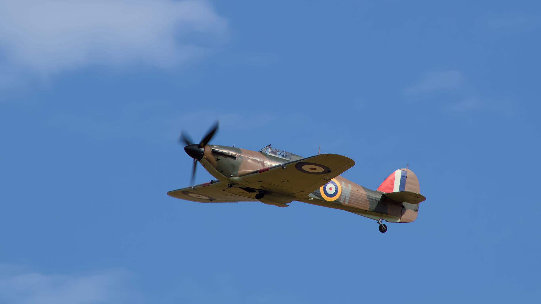 A classic wartime fighter plane soaring through a clear blue sky, showcasing aviation history.