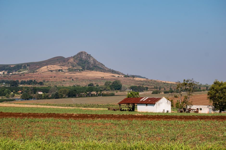 Beautiful rural landscape in Manzini, Eswatini featuring fields, a rustic building, and mountain views.
