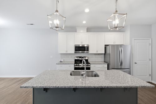 Free Spacious modern kitchen featuring granite countertops, stainless steel appliances, and elegant pendant lighting. Stock Photo